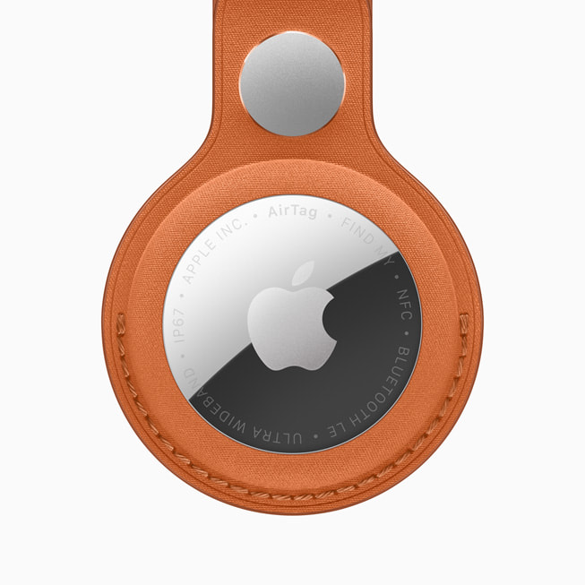 Apple AirTag in an orange FineWoven key ring, stainless steel face showing the Apple logo