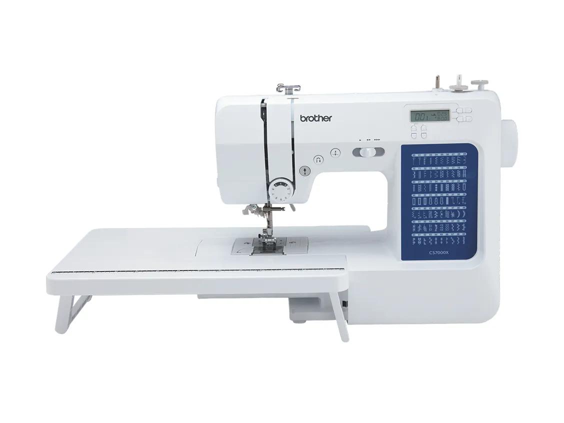 White Brother CS7000X computerized sewing machine with its detachable wide table fitted on the left and the table's folding support leg down, seen from the front at a slight angle on a plain white field; the brother wordmark sits on the arm, the LCD reads 001, and a dark blue stitch guide panel on the right of the body prints rows of stitch patterns above the model name CS7000X