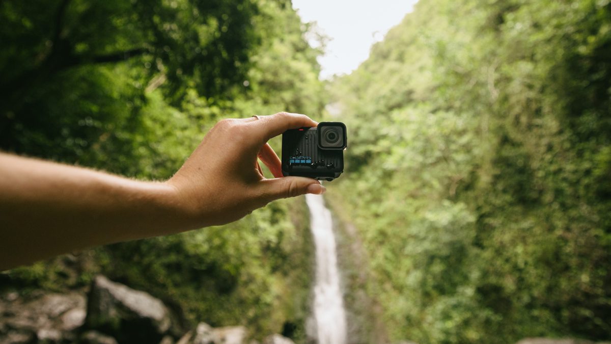 GoPro HERO compact action camera in black, seen from the front with the lens and folding mounting fingers
