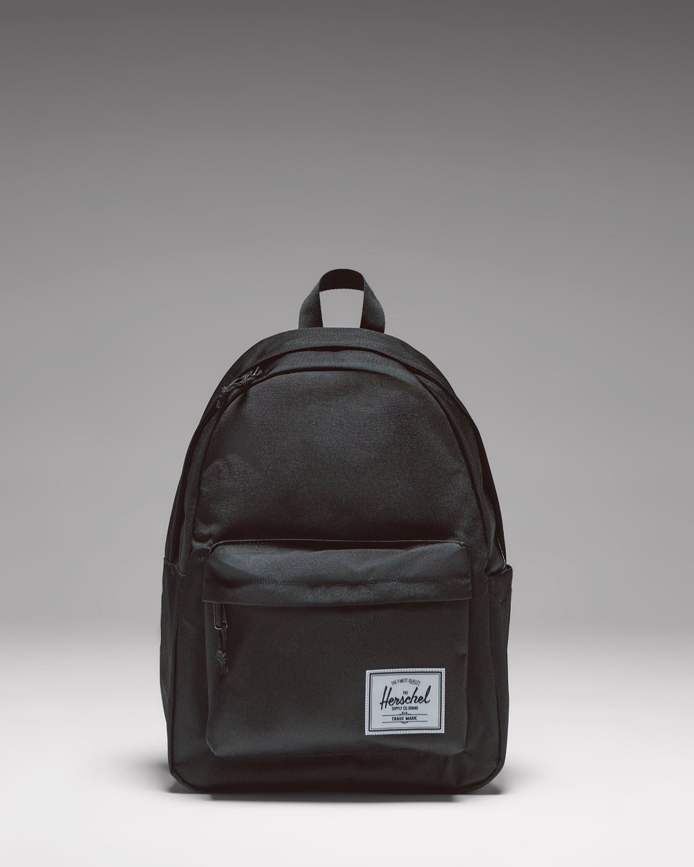 Black Herschel Classic Backpack, front view, with zippered front pocket and woven label