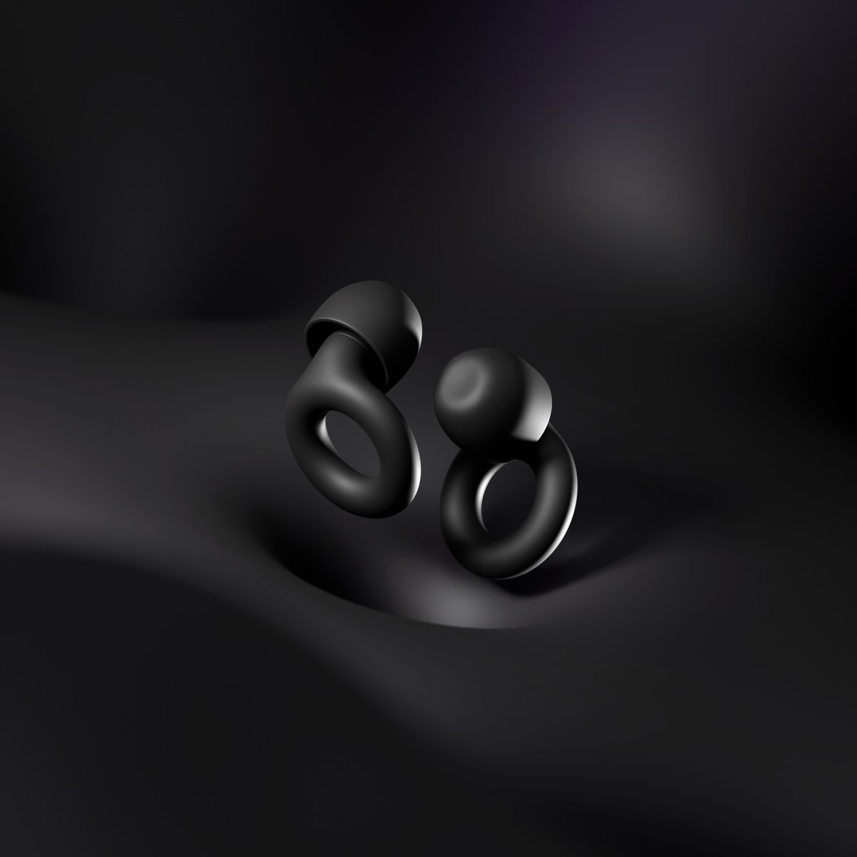 Two black Loop Quiet 2 silicone earplugs standing on a dark surface, ring bodies facing the camera