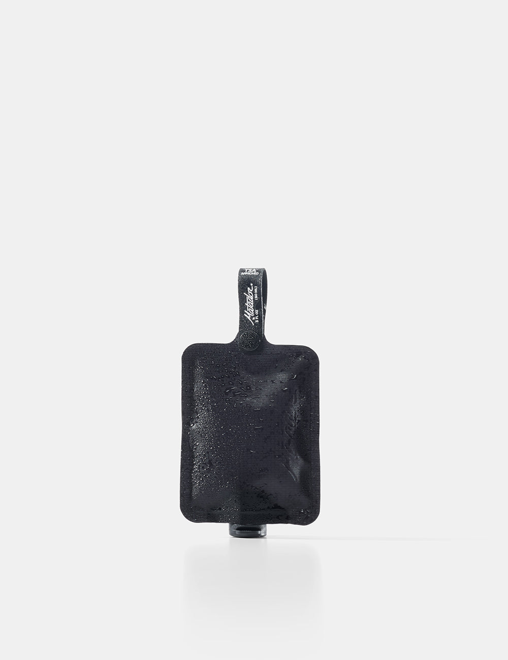 Matador FlatPak Toiletry Bottle in Charcoal, a flat black fabric bottle with a flip cap and snap loop, on a white background