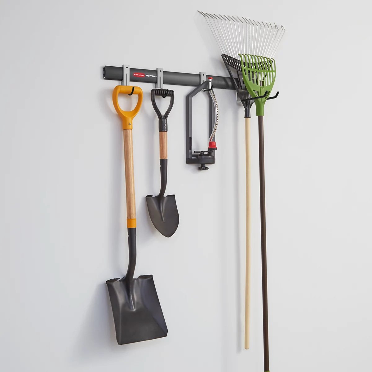 Black Rubbermaid FastTrack 32-inch garage rail with a multi-purpose hook, a scoop hook and two handle hooks mounted on it