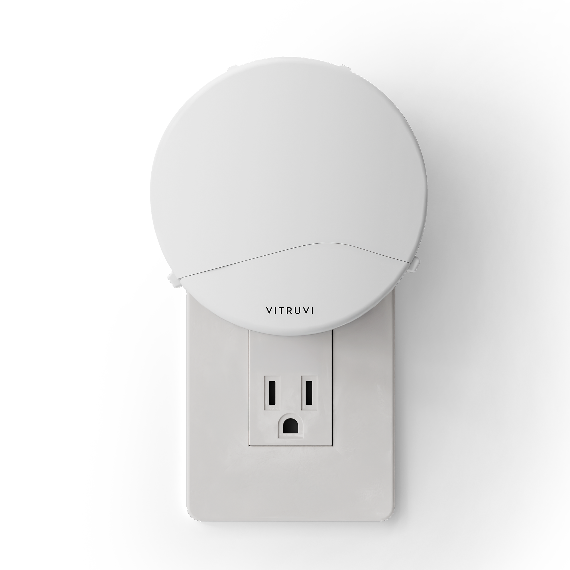 Vitruvi Push Plug-In Wall Diffuser in White plugged into a standard US wall outlet, its round face with the VITRUVI wordmark covering the upper receptacle while the lower one stays visible