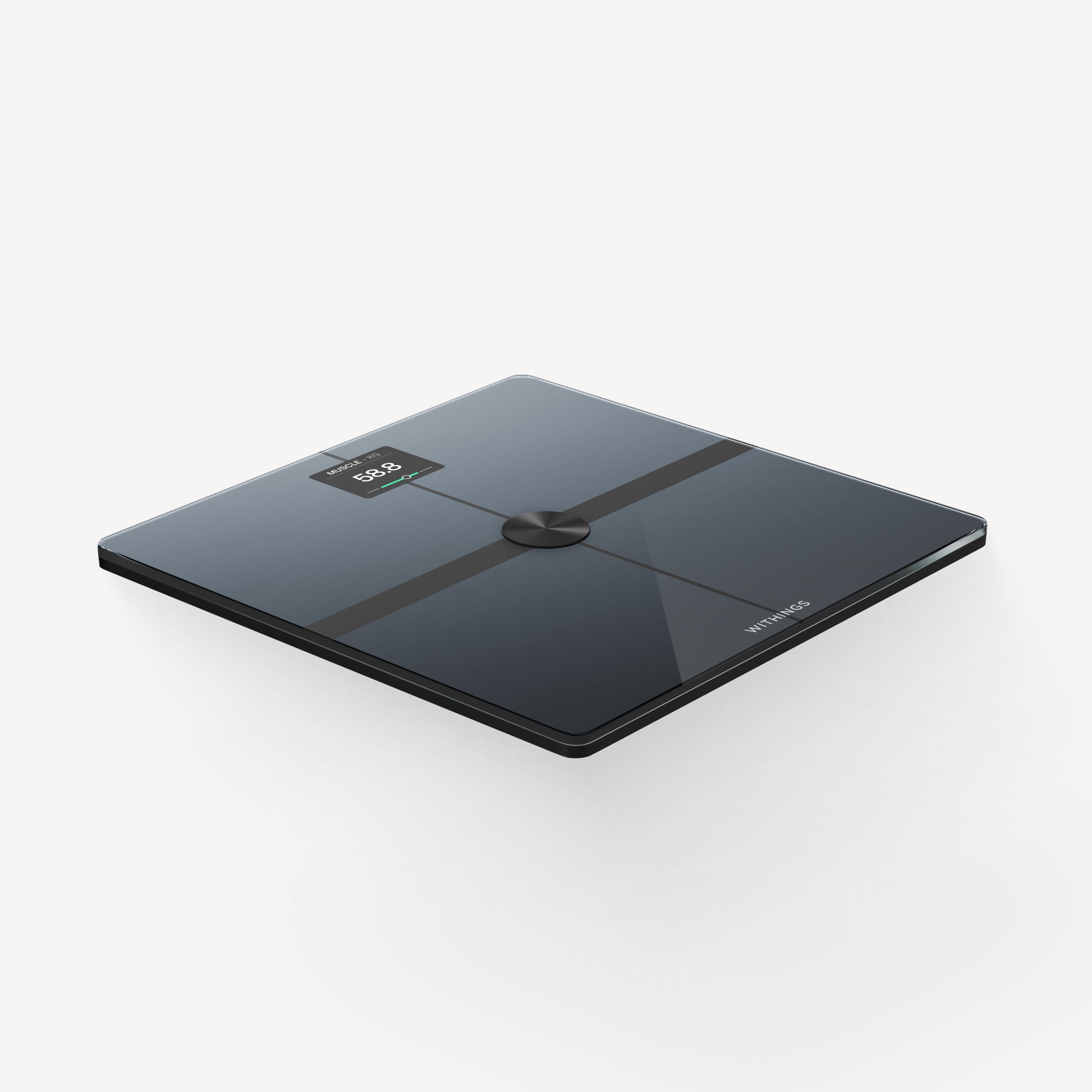 Withings' black Body Smart scale at a three-quarter top-down angle — the glass platform with four electrode stripes in a cross, a round metal button at the center, the small display reading a muscle-mass figure in kilograms, on a light warm-gray background