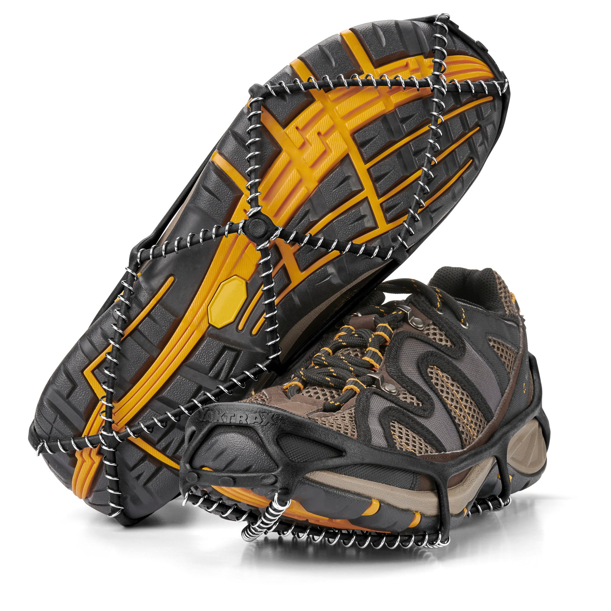 Yaktrax Walk traction cleats fitted to the soles of a pair of brown hiking shoes, viewed from below