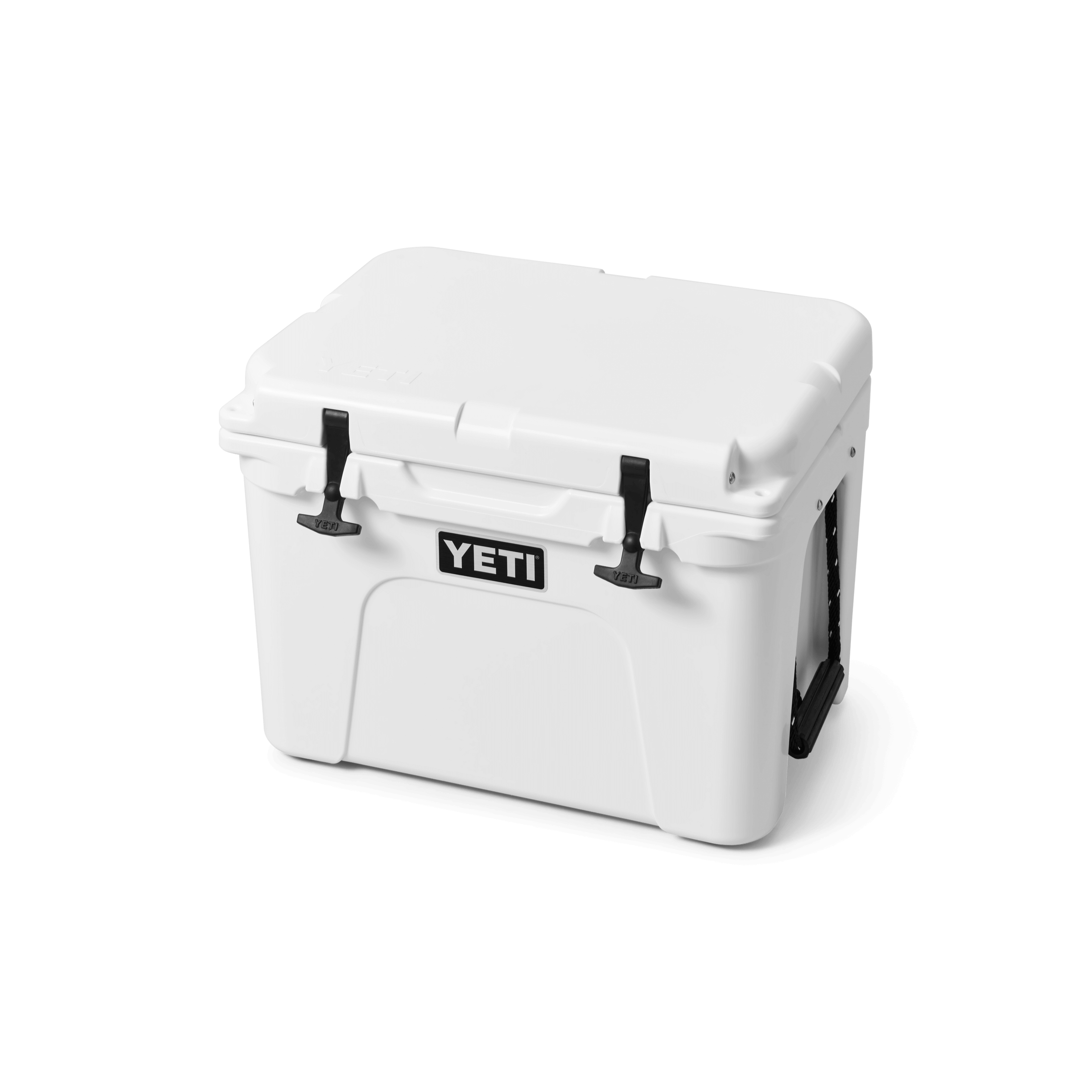 YETI Tundra 35 hard cooler in white, three-quarter front view with the lid closed, showing two black rubber T-latches, a black YETI logo plate on the front, and a rope handle at the right side