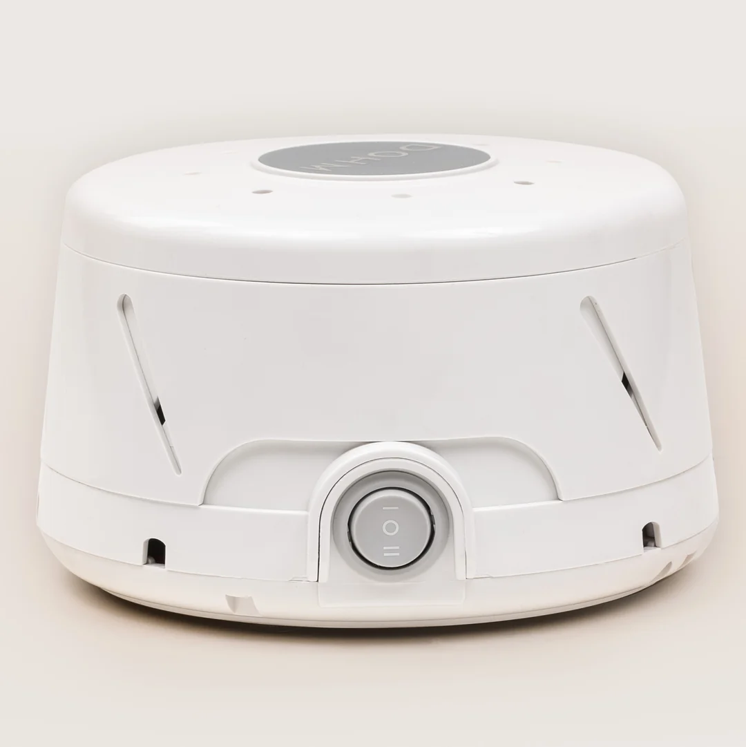 Yogasleep Dohm Classic white noise machine in white, showing the round DOHM badge on top, two angled vent slots in the shell and the front switch marked I, O and II