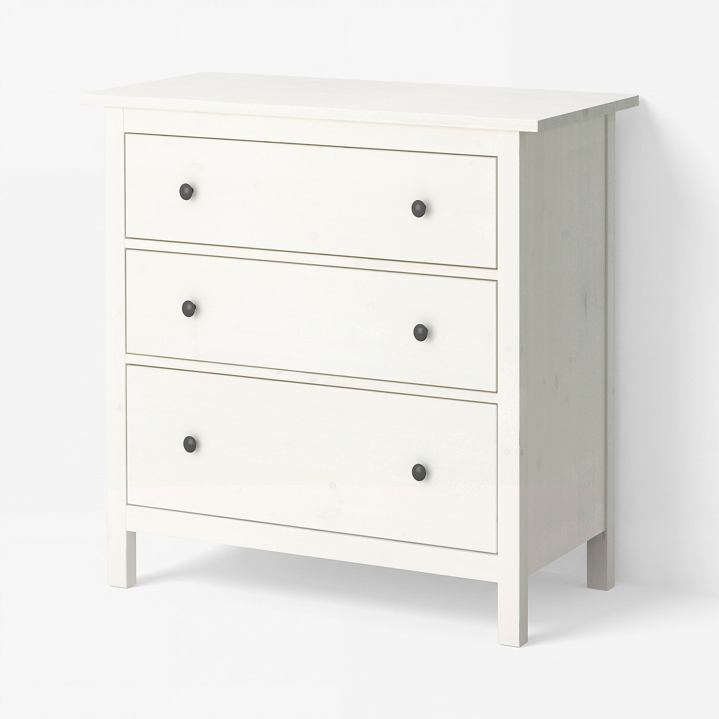 White-stained HEMNES chest of three drawers with dark grey round knobs on four legs, on a plain white background